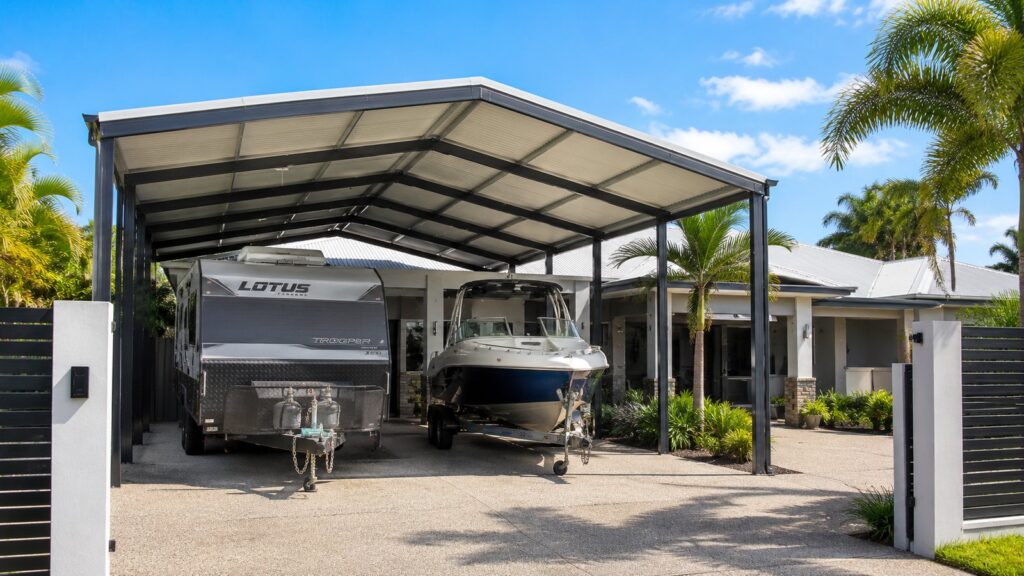 Caravan and boat stored under a high-clearance carport designed for oversized vehicles.